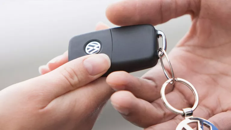 Dieses Bild zeigt zwei Hände, wobei eine Hand der anderen einen Autoschlüssel mit einem Volkswagen-Logo überreicht.