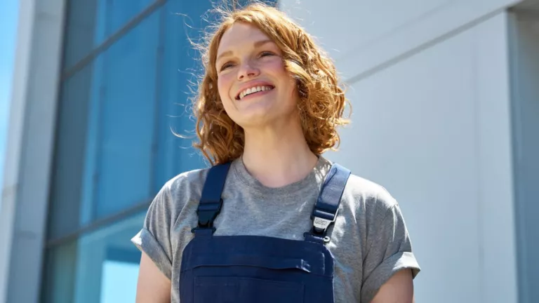 Lächelnde VW-Service-Mitarbeiterin mit Arbeitshandschuhen in der Hand.