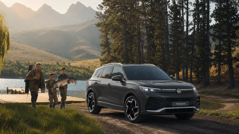 VW Tiguan in grau in der Natur vor einem See mit einer Familie.