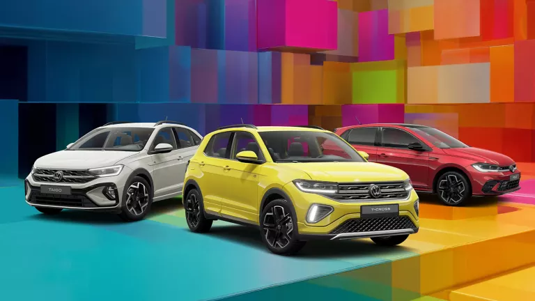 Drei VW-Modelle vor einem bunten, geometrischen Hintergrund aus leuchtenden 3D-Blöcken.