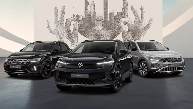 Drei VW modelle in Schwarz und Grau auf schwarzem Boden vor einer Wand mit abstrakter Kunst.