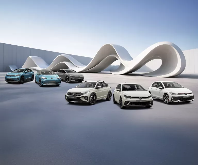 VW Modelle vor einer futuristischen Skulpturform, im Hintergrund eine Mauer