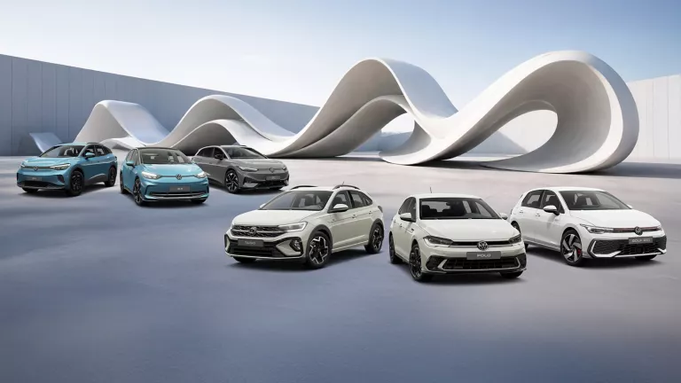 VW-Modelle vor einer futuristischen Skulpturform, im Hintergrund eine Mauer