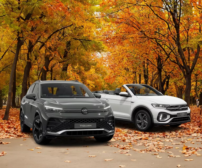 VW Tiguan und T-Roc Cabriolet parken, im Hintergrund Bäume mit bunten Blättern