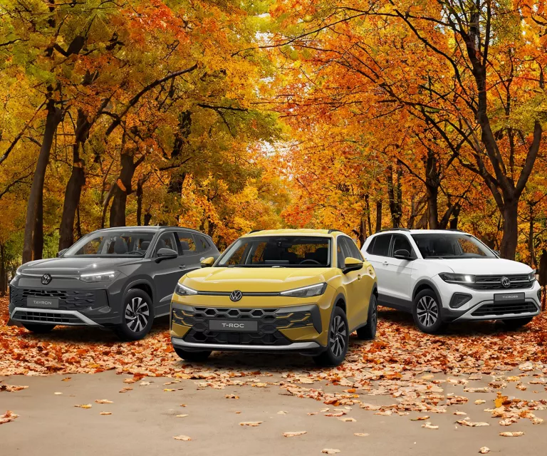 VW Tayron, T-Roc und T-Cross parken, im Hintergrund Bäume mit bunten Blättern