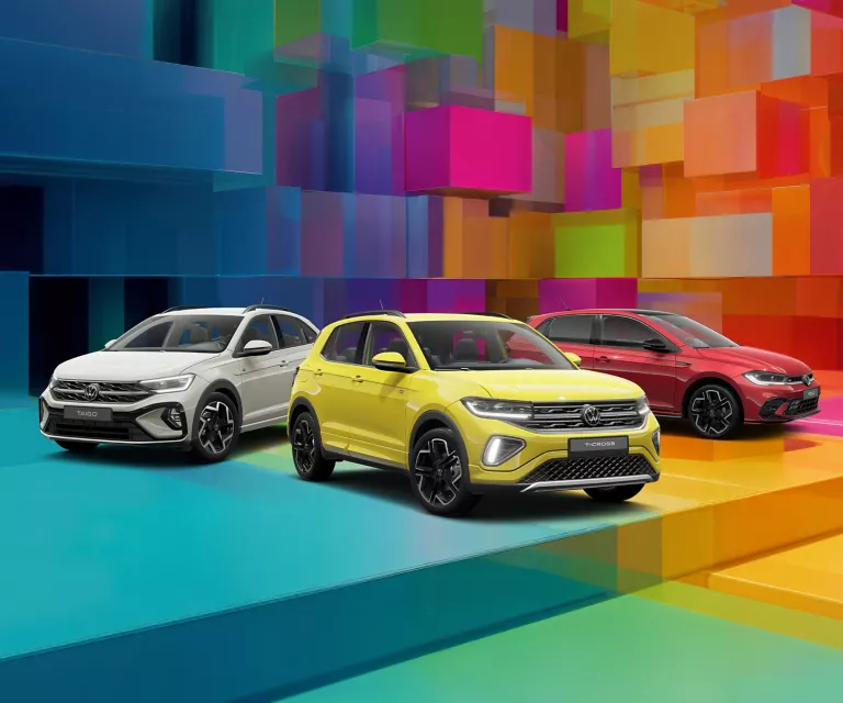 Drei VW-Modelle vor einem bunten, geometrischen Hintergrund aus leuchtenden 3D-Blöcken.
