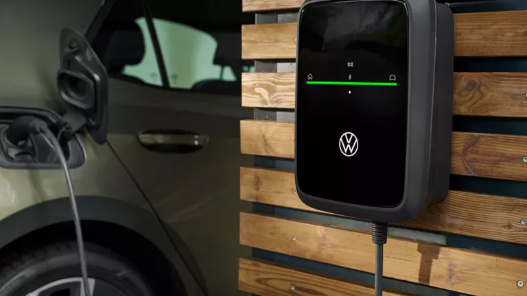 VW ID., daneben ein ID. Charger von der Volkswagen Group Charging GmbH (Elli) an der Wand.