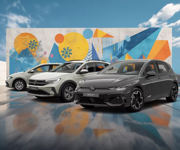 Drei VW-Modelle vor einer Wand mit winterlich, farbenfrohem, geometrischem Street-Art-Graffiti.