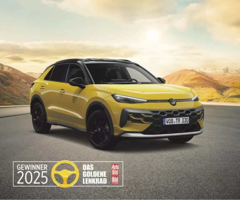 Gelber VW T-Roc steht auf einer Straße, im Hintergrund Berge