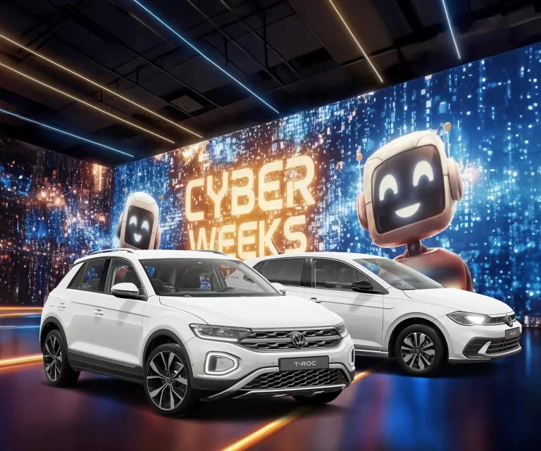 Zwei VW-Modelle vor einer großen digitalen Wand mit leuchtendem Schriftzug "CYBER WEEKS" und zwei lächelnden Roboter.