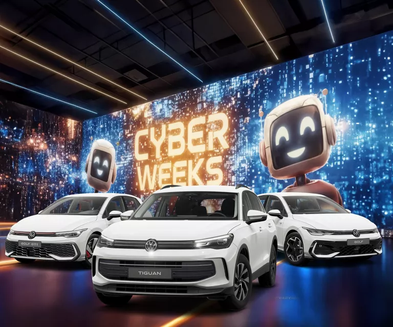 Drei VW-Modelle vor einer großen digitalen Wand mit leuchtendem Schriftzug "CYBER WEEKS" und zwei lächelnden Roboter.