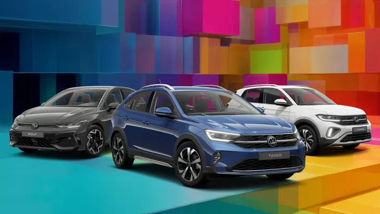 Drei VW-Modelle vor einem bunten, geometrischen Hintergrund aus leuchtenden 3D-Blöcken.