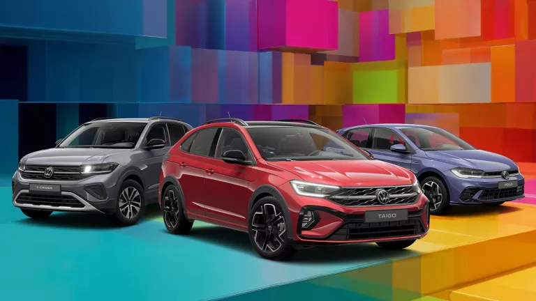 Drei VW-Modelle vor einem bunten, geometrischen Hintergrund aus leuchtenden 3D-Blöcken.