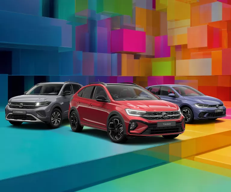 Drei VW-Modelle vor einem bunten, geometrischen Hintergrund aus leuchtenden 3D-Blöcken.