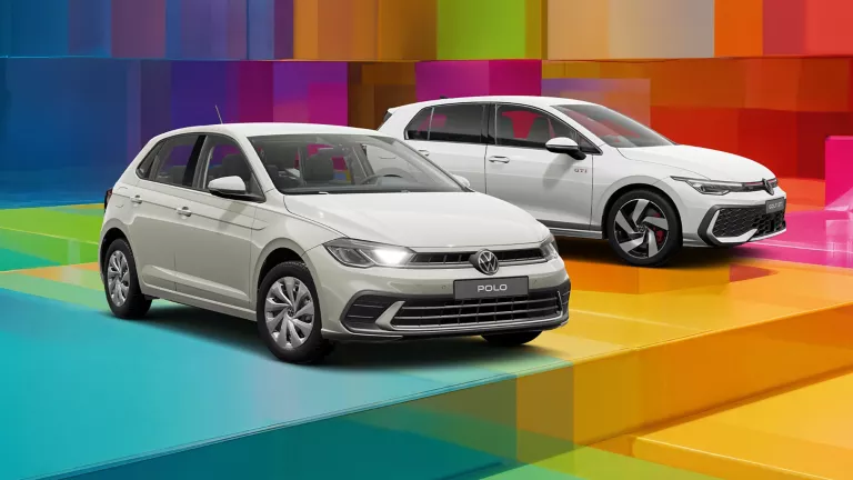 Drei VW-Modelle vor einem bunten, geometrischen Hintergrund aus leuchtenden 3D-Blöcken.