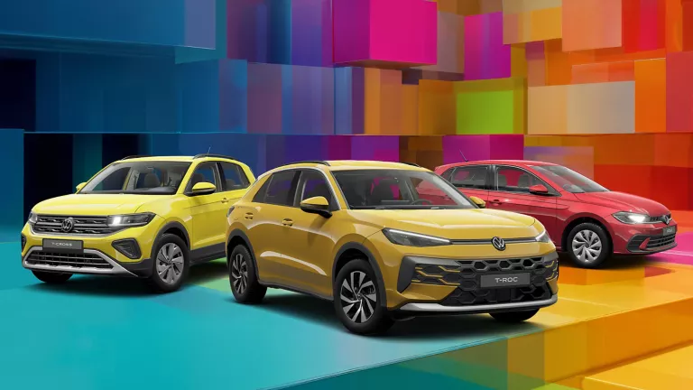 Drei VW-Modelle vor einem bunten, geometrischen Hintergrund aus leuchtenden 3D-Blöcken.