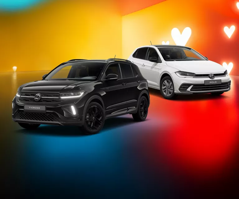 Zwei VW-Modelle in Weiß und Schwarz vor gelb-rotem Hintergrund mit weißen Herzsymbolen.