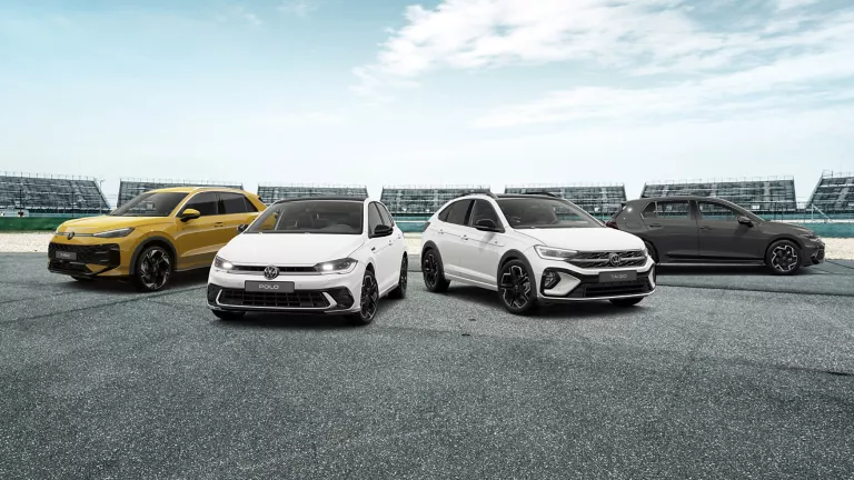 Vier VW Modelle stehen auf einer Straße, im Hintergrund ein Stadion