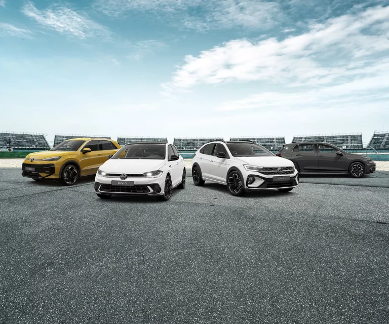 Vier VW Modelle stehen auf einer Straße, im Hintergrund ein Stadion