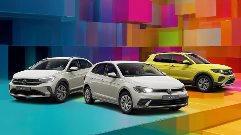 Drei VW-Modelle vor einem bunten, geometrischen Hintergrund aus leuchtenden 3D-Blöcken.