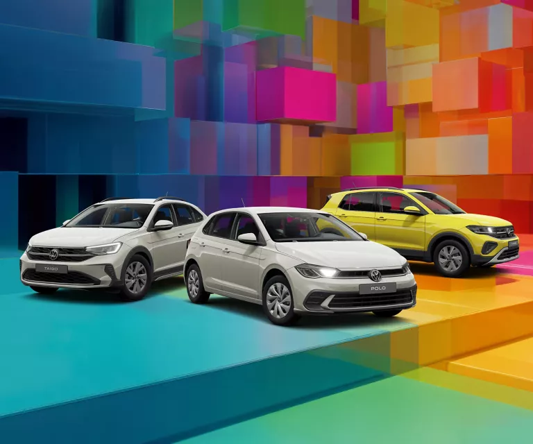 Drei VW-Modelle vor einem bunten, geometrischen Hintergrund aus leuchtenden 3D-Blöcken.