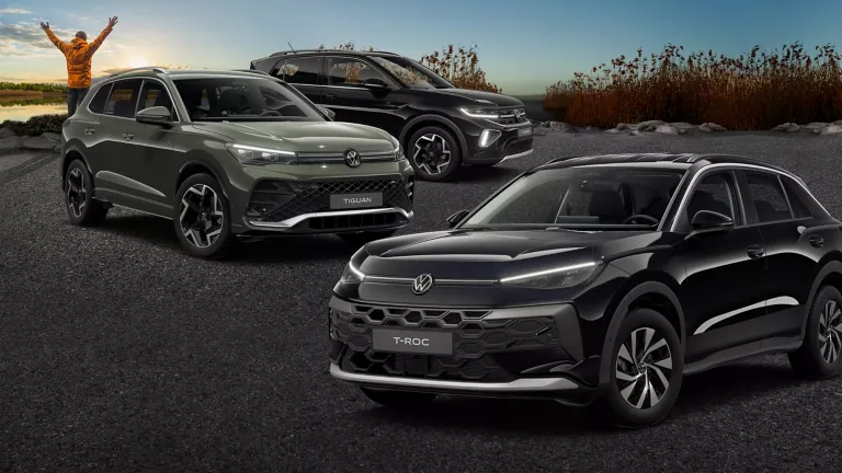 3 VW Modelle die auf Asphalt stehen, vor Schilf und einem See.