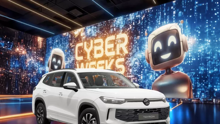 Weißer VW Tayron Life vor einer großen digitalen Wand mit leuchtendem Schriftzug "CYBER WEEKS" und zwei lächelnden Roboter.