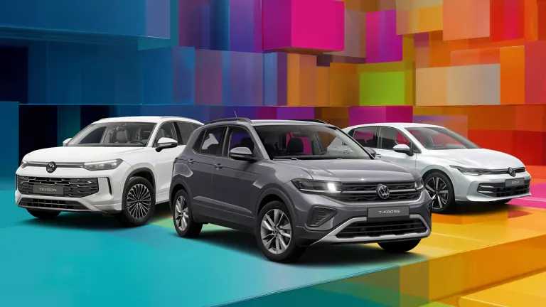 Drei VW-Modelle vor einem bunten, geometrischen Hintergrund aus leuchtenden 3D-Blöcken.