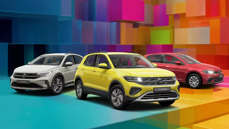 Drei VW-Modelle vor einem bunten, geometrischen Hintergrund aus leuchtenden 3D-Blöcken.