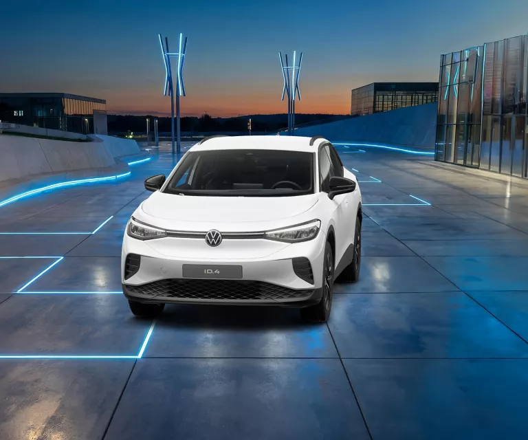 Weißer VW ID.4 auf einem futuristischen Platz mit blauen Leuchtlinien und moderner Architektur im Hintergrund.