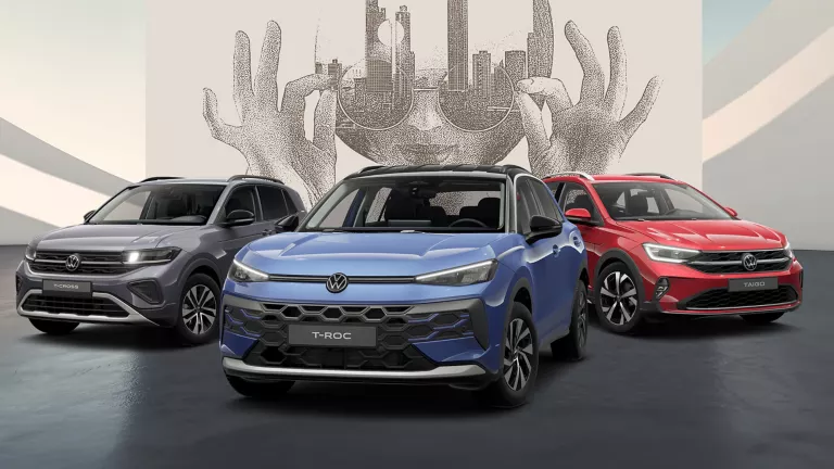 Drei VW Modelle auf schwarzem Boden vor einer Wand mit abstrakter Kunst.