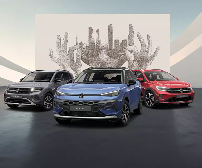 Drei VW Modelle auf schwarzem Boden vor einer Wand mit abstrakter Kunst.