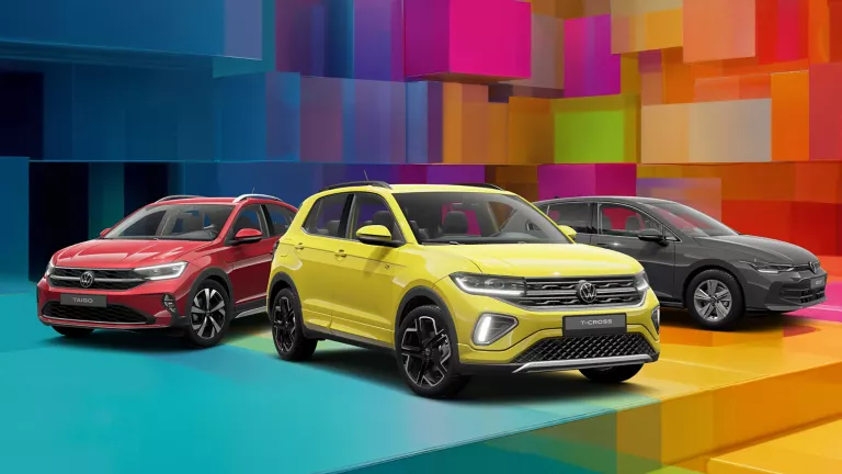 Drei VW-Modelle vor einem bunten, geometrischen Hintergrund aus leuchtenden 3D-Blöcken.