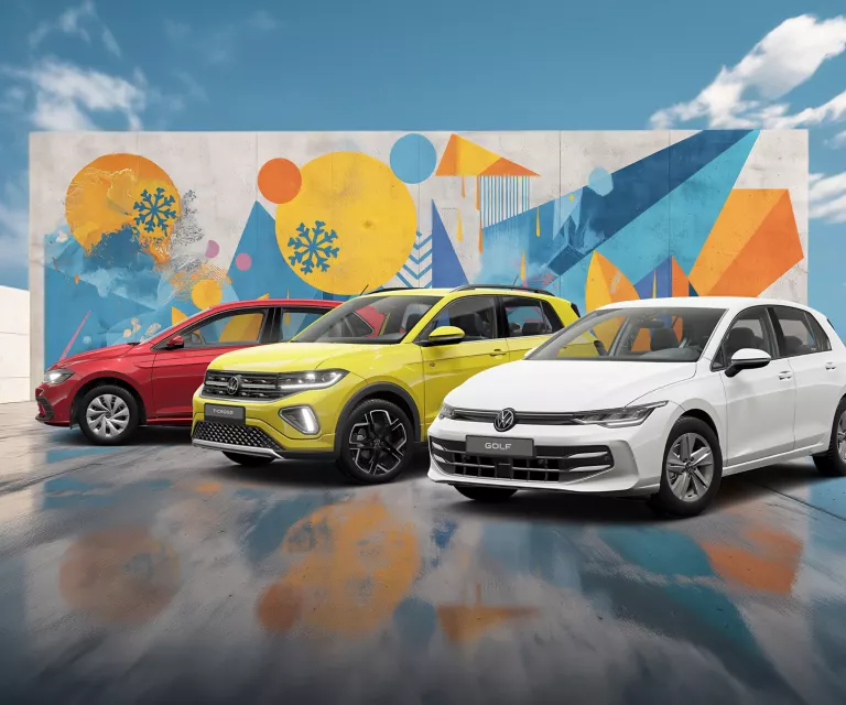 Drei VW-Modelle stehen nebeneinander vor einer Wand mit winterlich, farbenfrohem, geometrischem Street-Art-Graffiti.