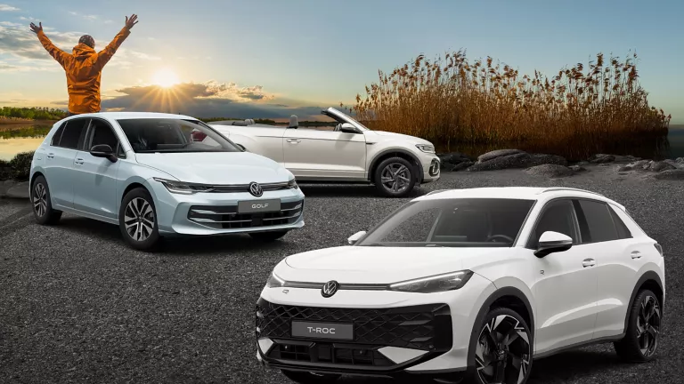 Drei VW-Modelle stehen auf Asphalt, vor Schilf und einem See.