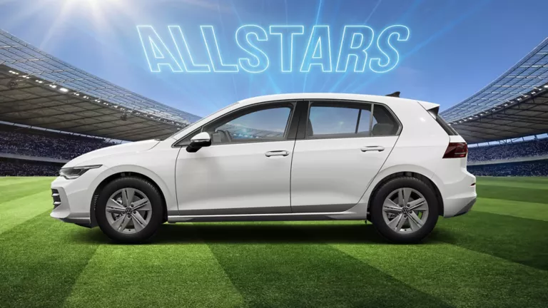 Seitenansicht auf eines weißen VW Golf auf einem Fußballfeld im Stadion, darüber leuchtet der Schriftzug „ALLSTARS“.