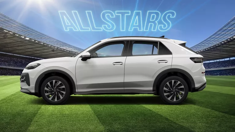 Seitenansicht auf eines weißen VW T-Roc auf einem Fußballfeld im Stadion, darüber leuchtet der Schriftzug „ALLSTARS“.
