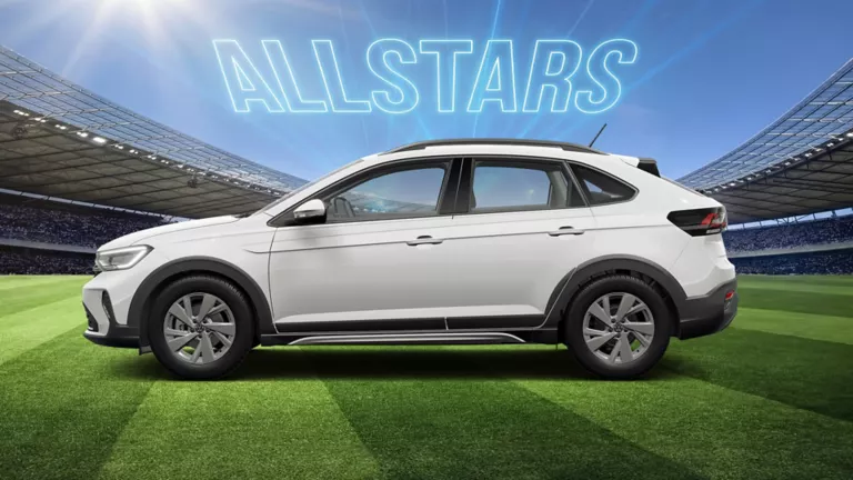 Seitenansicht auf eines weißen VW Taigo auf einem Fußballfeld im Stadion, darüber leuchtet der Schriftzug „ALLSTARS“.