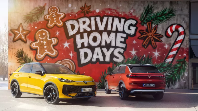 Zwei VWT-Roc, ein gelber von vorne links und ein roter von hinten rechts, vor einer Wand mit dem Schriftzug "DRIVING HOME DAYS".