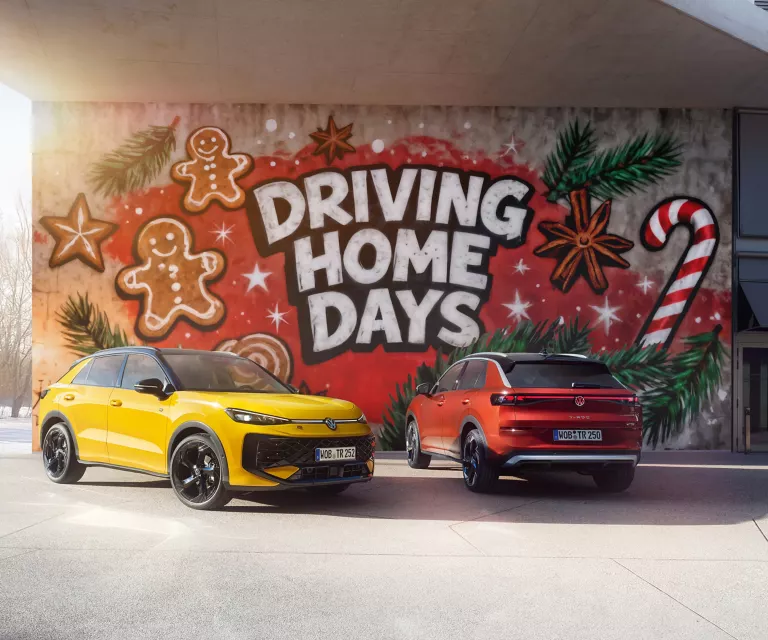 Zwei VWT-Roc, ein gelber von vorne links und ein roter von hinten rechts, vor einer Wand mit dem Schriftzug "DRIVING HOME DAYS".