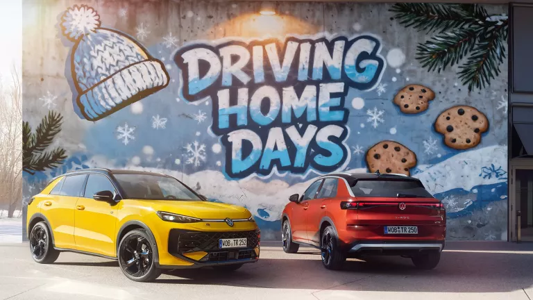 Zwei VWT-Roc, ein gelber von vorne links und ein roter von hinten rechts, vor einer Wand mit dem Schriftzug "DRIVING HOME DAYS".