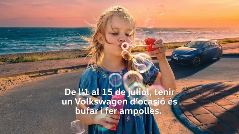 Una nena bufant ampollas menjant un gelat amb un Volkswagen blau a la platja