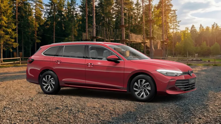 Seitenansicht auf eines Roten VW Passat auf einem Schotterplatz vor einem Wald-Kletterpark.