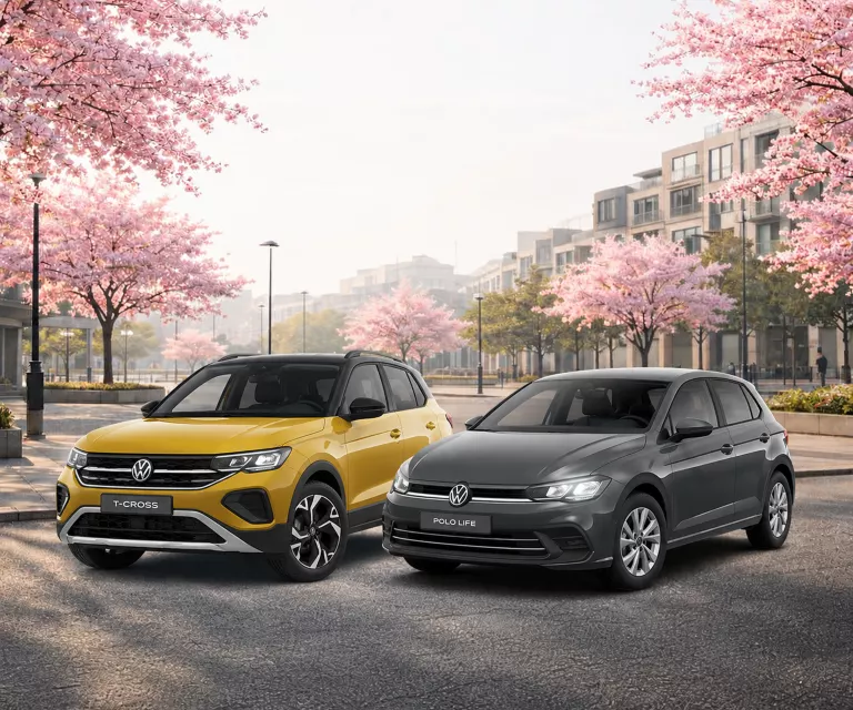 VW T-Roc und Tiguan auf einen Parkplatz mit blühenden Bäumen.