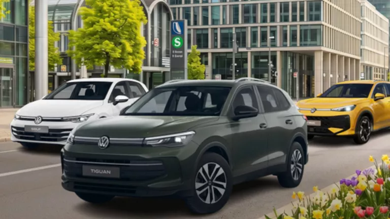 Ein weißer VW Golf, ein gelber VW T-Roc & ein grauer VW Tiguan stehen in einer urbanen Straße umgeben von blühenden Blumen.