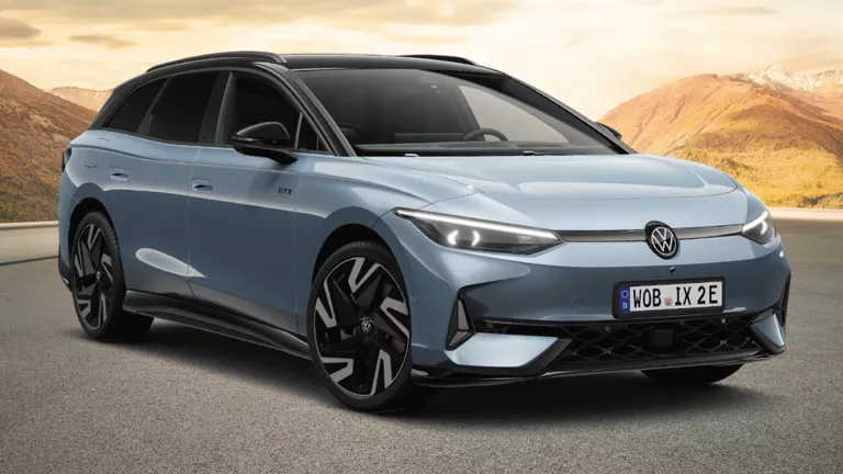 Grau­er VW ID.7 GTX Tourer auf einer leeren Bergstraße mit sanften Hügeln und Bergen im warmen Abendlicht, ausgezeichnet als „Gewinner 2025 – Das Goldene Lenkrad“.