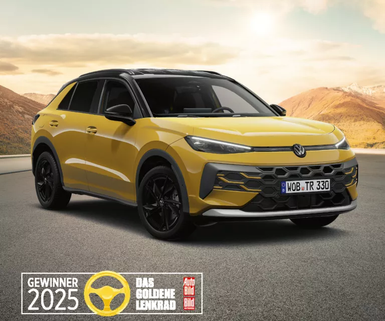 Gelber VW T-Roc auf einer leeren Bergstraße mit sanften Hügeln und Bergen im warmen Abendlicht, ausgezeichnet als „Gewinner 2025 – Das Goldene Lenkrad“.
