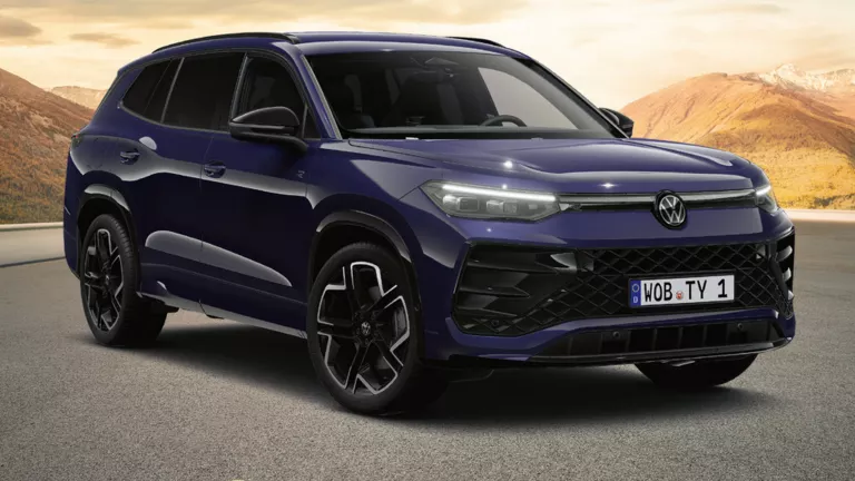 Schwartzer VW Tayron auf einer leeren Bergstraße mit sanften Hügeln und Bergen im warmen Abendlicht, ausgezeichnet als „Gewinner 2025 – Das Goldene Lenkrad“.