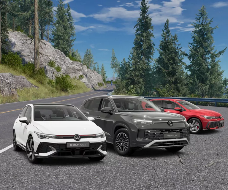 Drei VW-Sportmodelle stehen am Rand einer Bergstraße, im Hintergrund sind Bäume und der Himmel zu sehen.