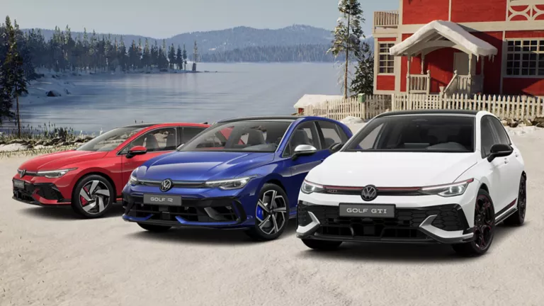 Drei VW Modelle stehen vor verschneitem Haus, im Hintergrund ein See